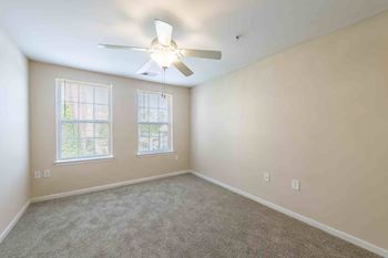 A room with a ceiling fan and two windows.